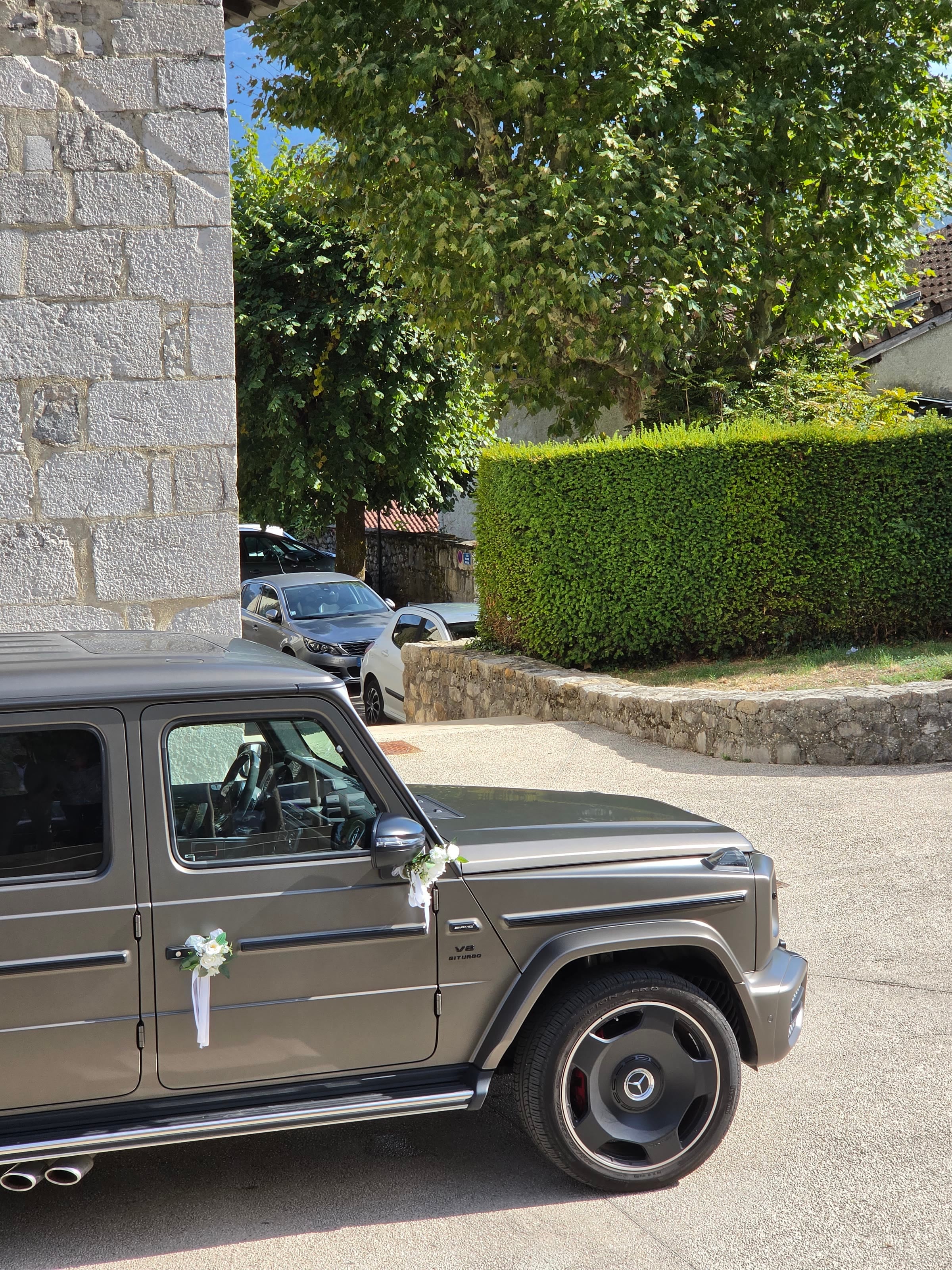 Mercedes Classe G 63 AMG 2025 fleuri, de trois quarts, devant l'église