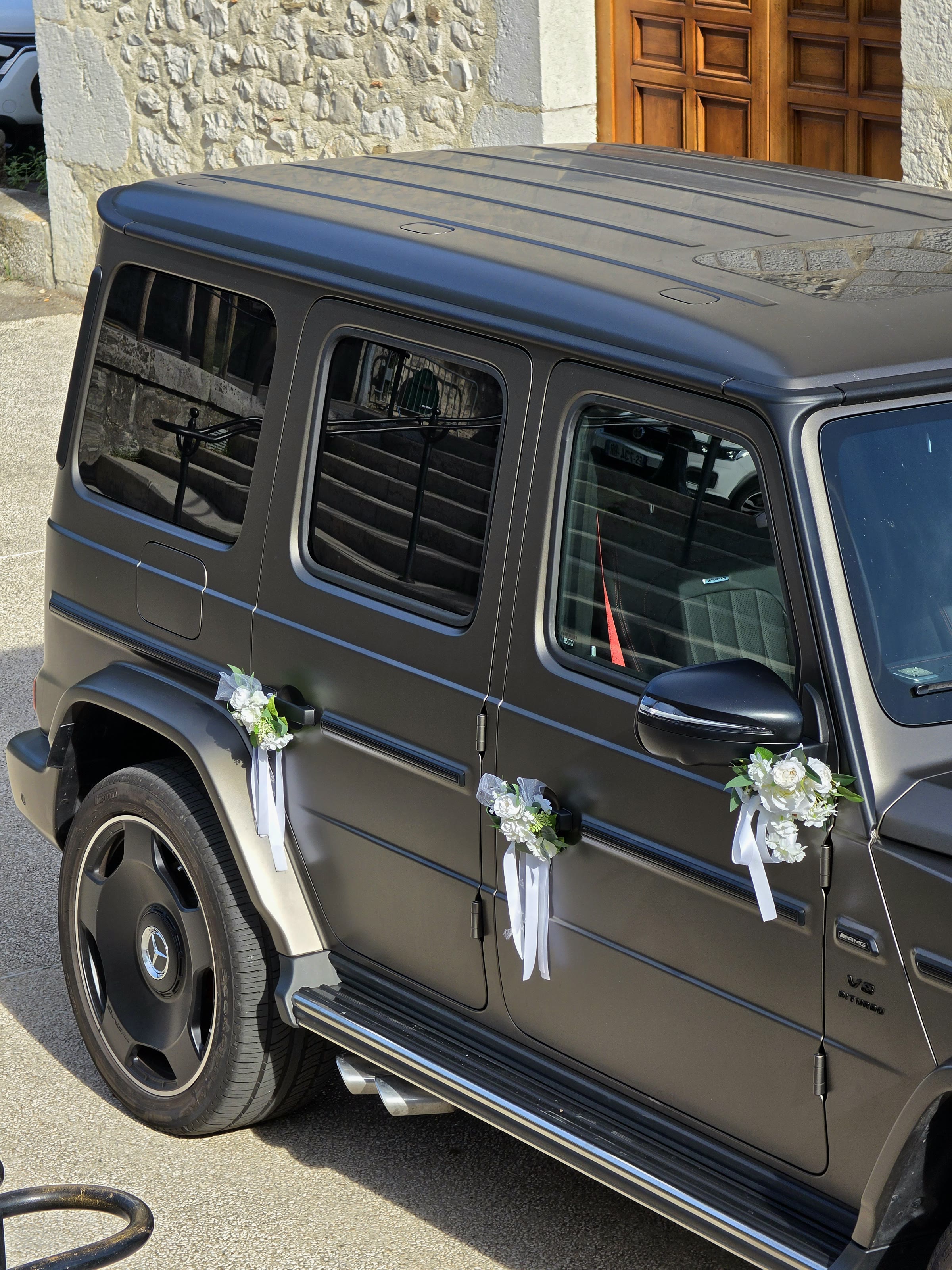 Classe G 63 AMG 2025 de profil devant la porte en bois de l'église