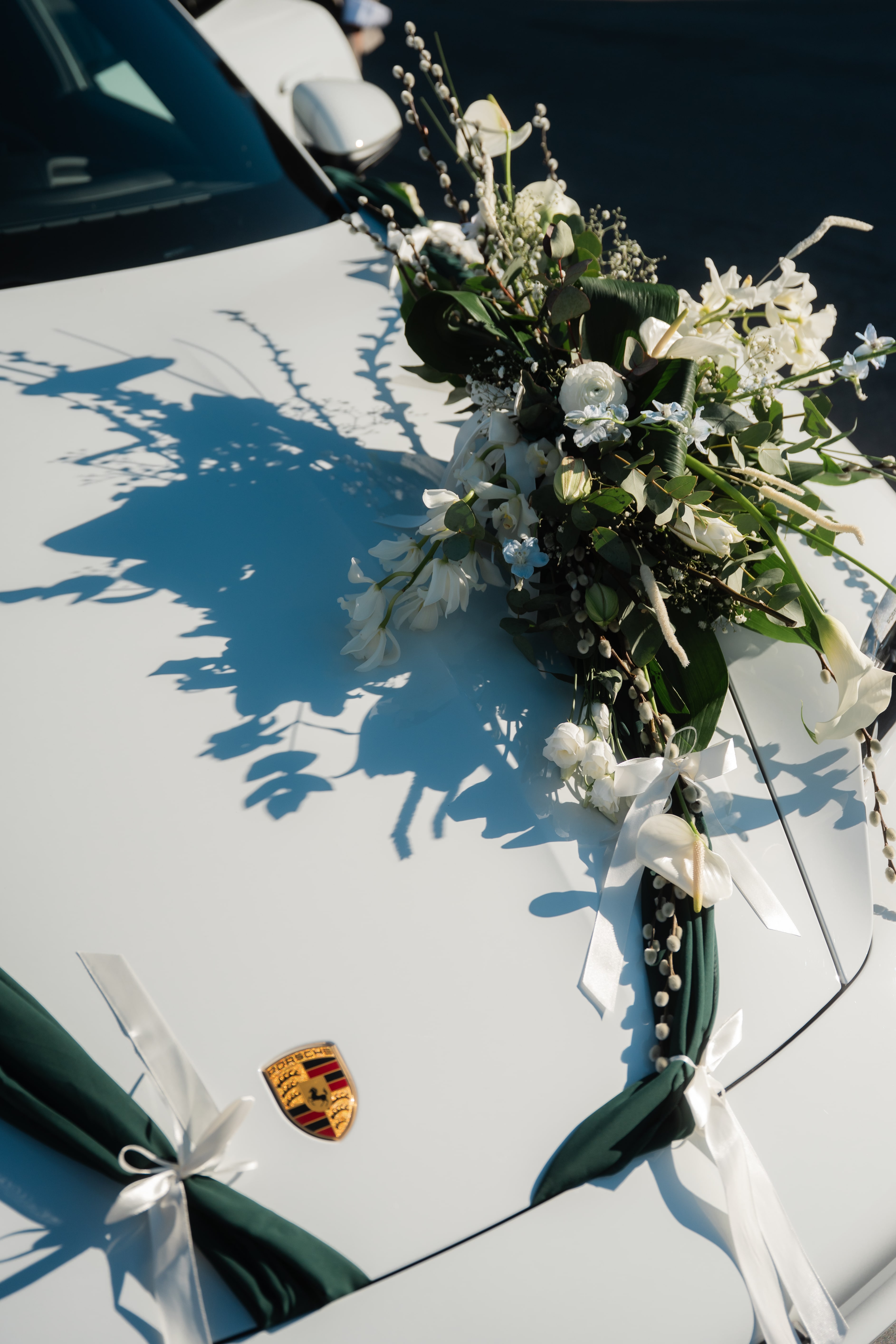 Composition florale blanche et rubans posés sur le capot de la Porsche Taycan