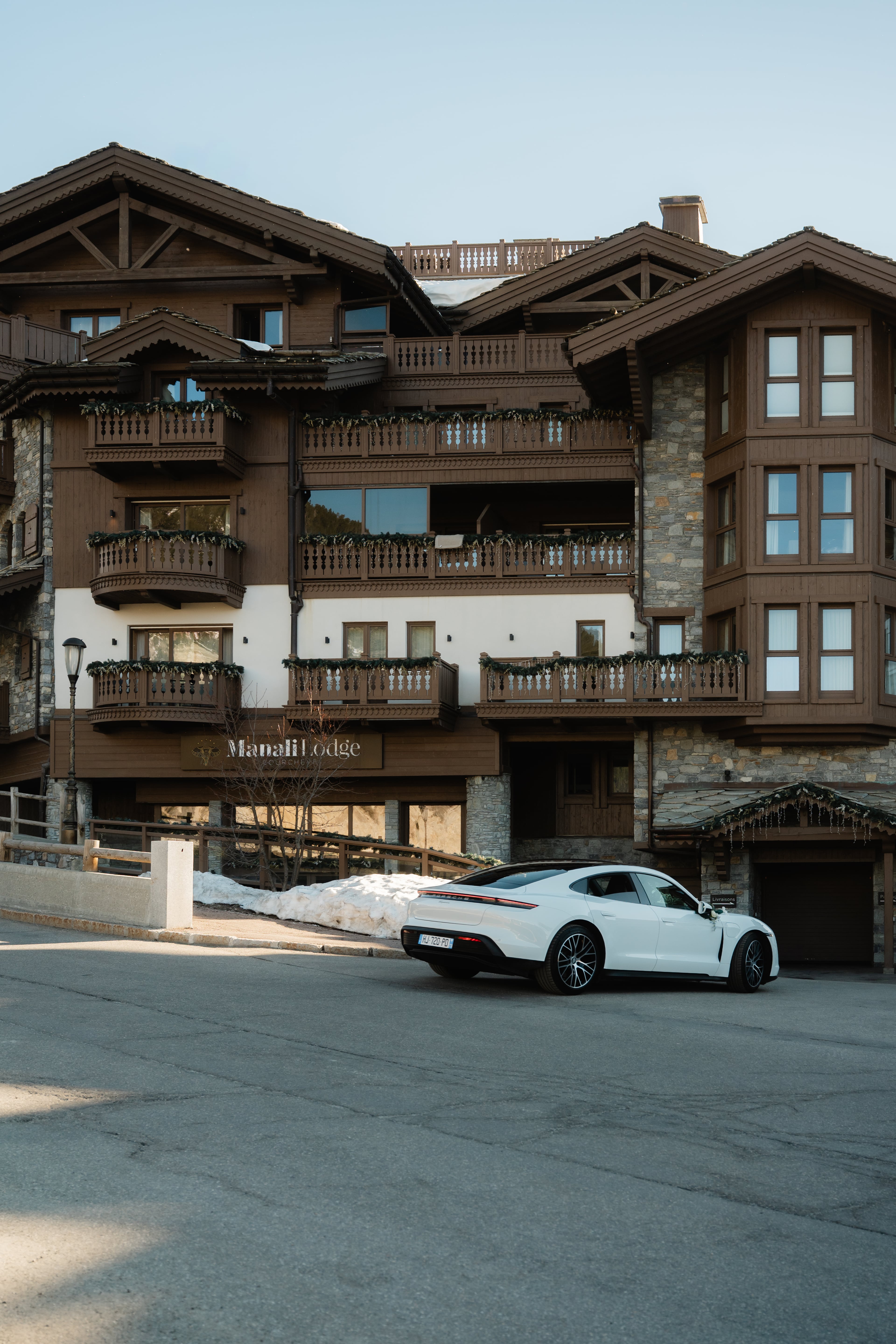 Porsche Taycan blanche devant les chalets de Courchevel
