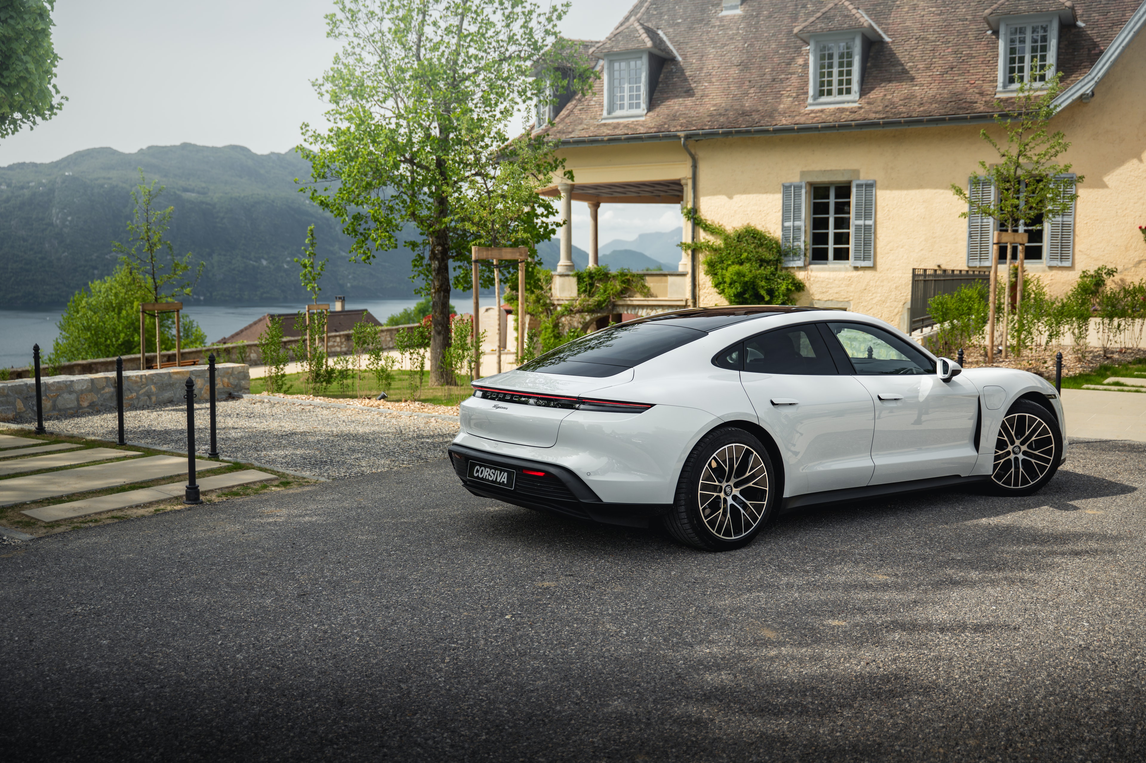 Porsche Taycan blanche sur la route, au bord du lac, entre deux étapes du jour J